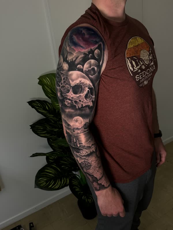 Full sleeve with skull in clouds, moonlit ship and lighthouse scene, compass and map