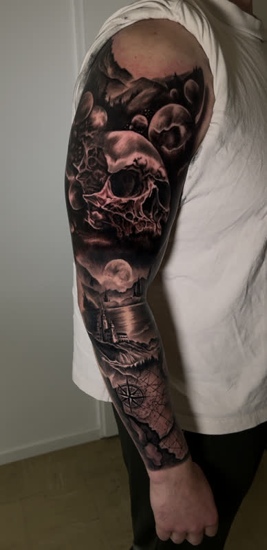 Full sleeve with skull in clouds, moonlit ship and lighthouse scene, compass and map